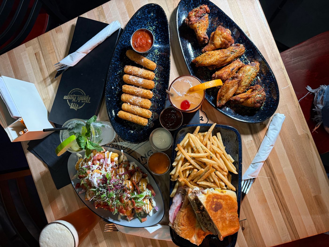A table of scratch-made plates at The Nash Keys in downtown Clearwater &mdash; Nashville hot wings, mozzarella sticks, loaded tostones and a Cuban sandwich with truffle fries